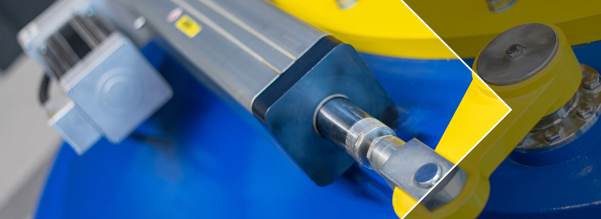 Nahaufnahme eines blauen und gelben mechanischen Bauteils mit Metallzylinder und Schrauben