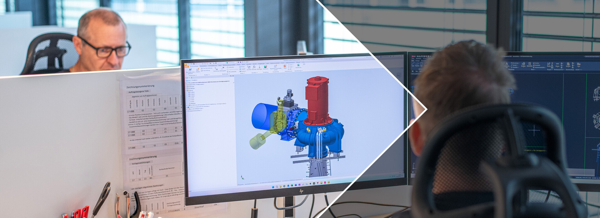 Zwei Personen sitzen an Schreibtischen mit Computermonitoren, auf einem Bildschirm ist eine technische 3D-Konstruktion zu sehen.